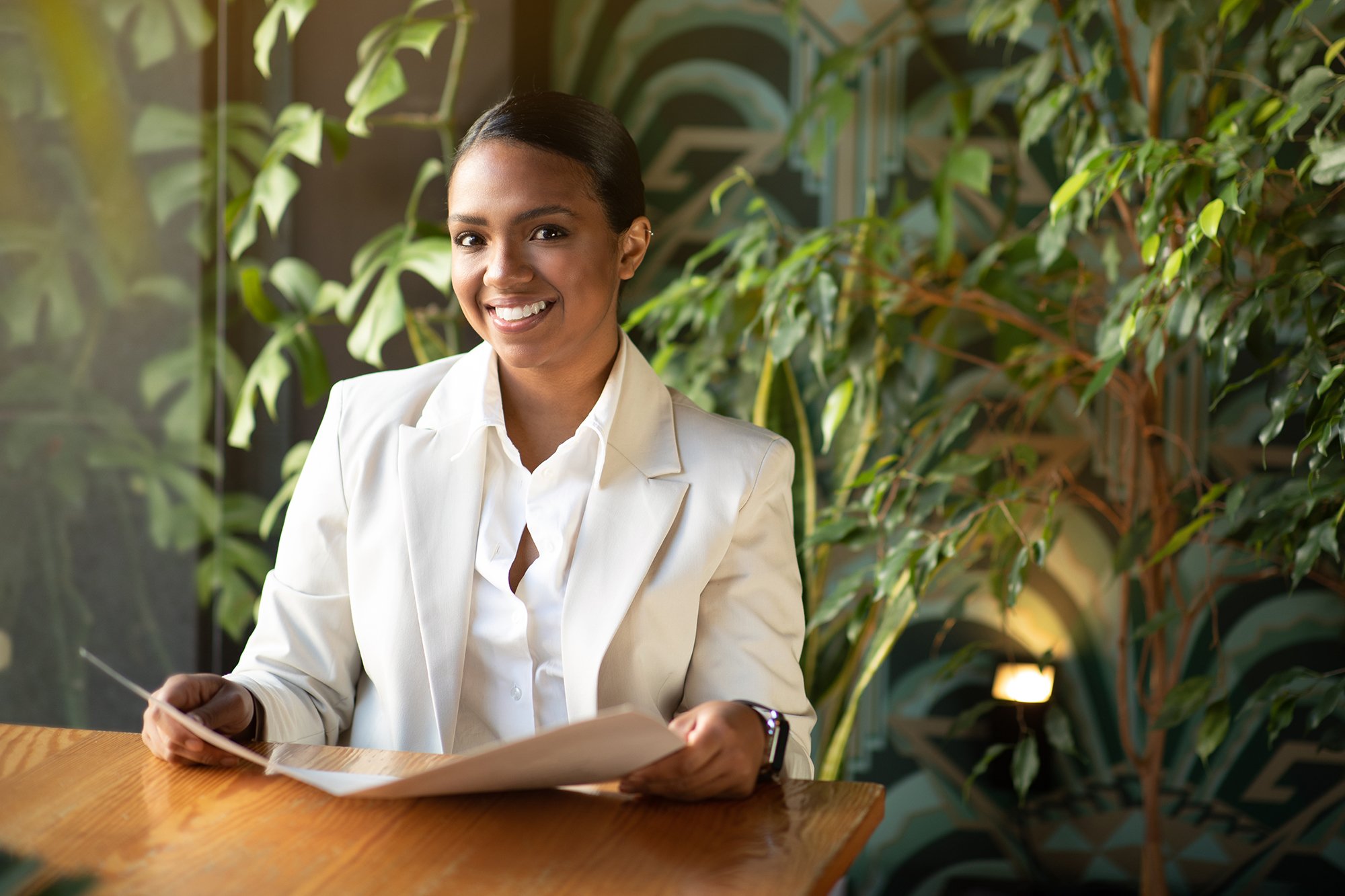 cheerful-young-black-woman-in-white-suit-sitting-a-2025-03-18-17-40-56-utc